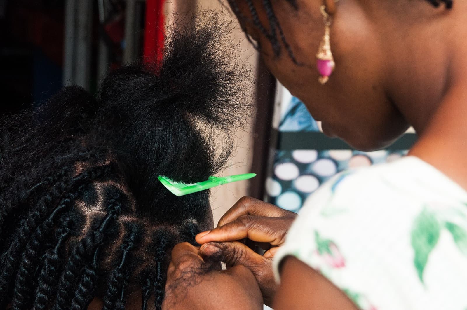 Close-up of a stylist parting and braiding a client’s hair in a salon.